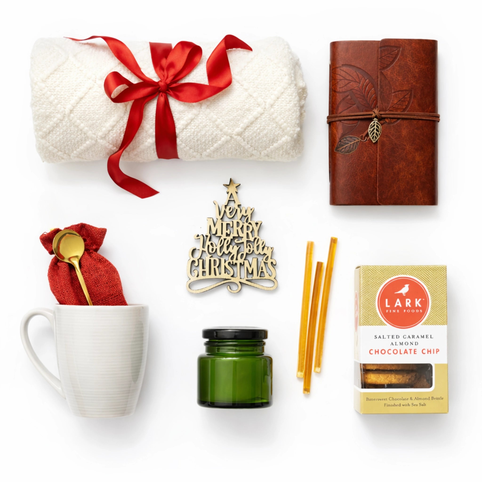 Top down flat lay view of Holiday Warmth gift set items including throw blanket, leather journal and candle.