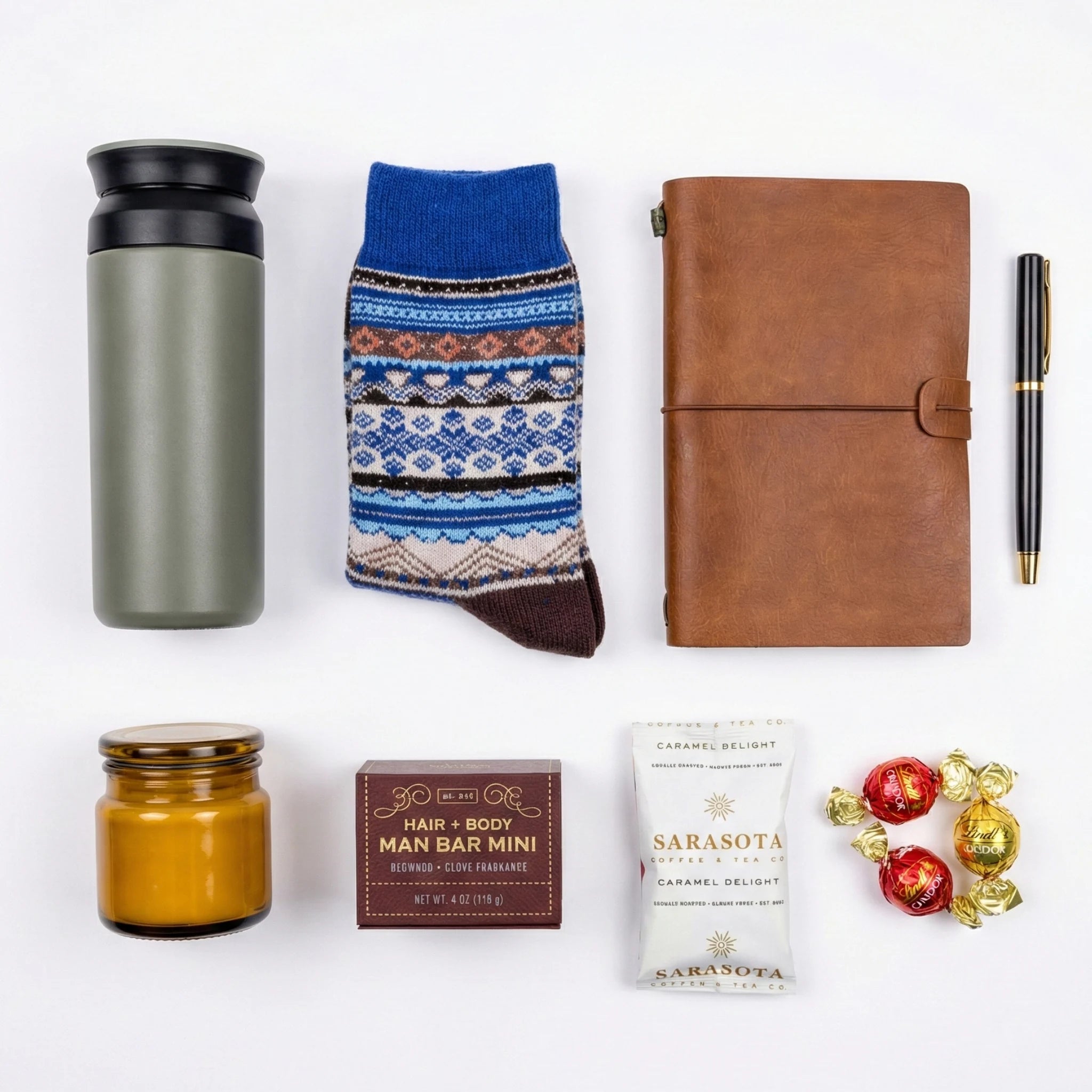 Top down flat lay view of Men's gift box items including travel mug and notebook