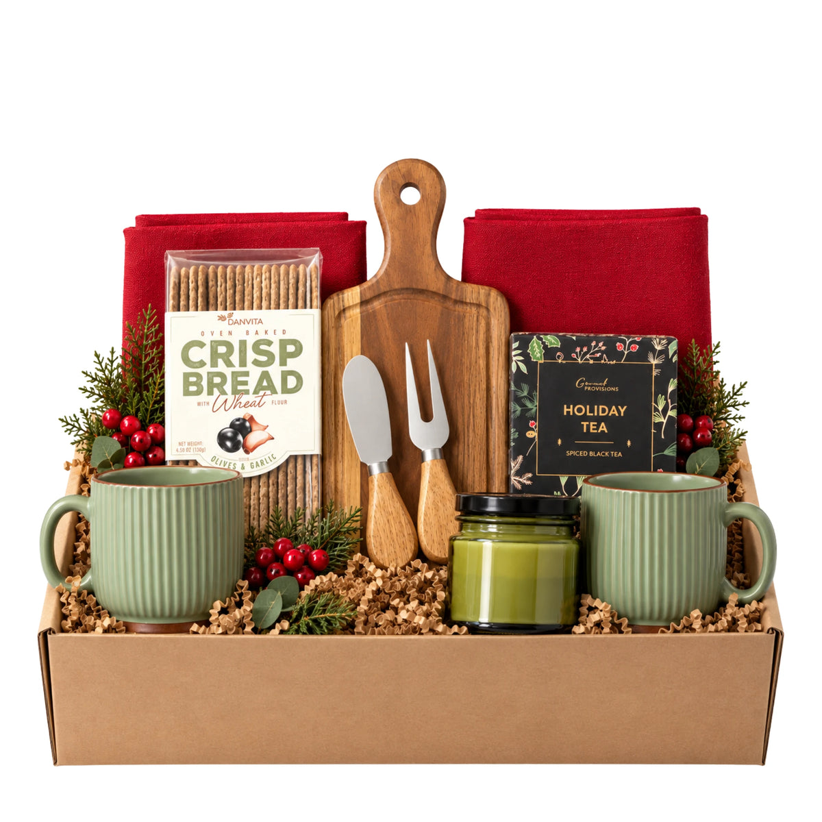 I'll Be Home Christmas gift box featuring acacia wood charcuterie board with cheese knives, two sage ceramic mugs, spiced holiday tea box, artisan flatbread crackers, green candle jar, red kitchen towels, and cedar berry sprigs