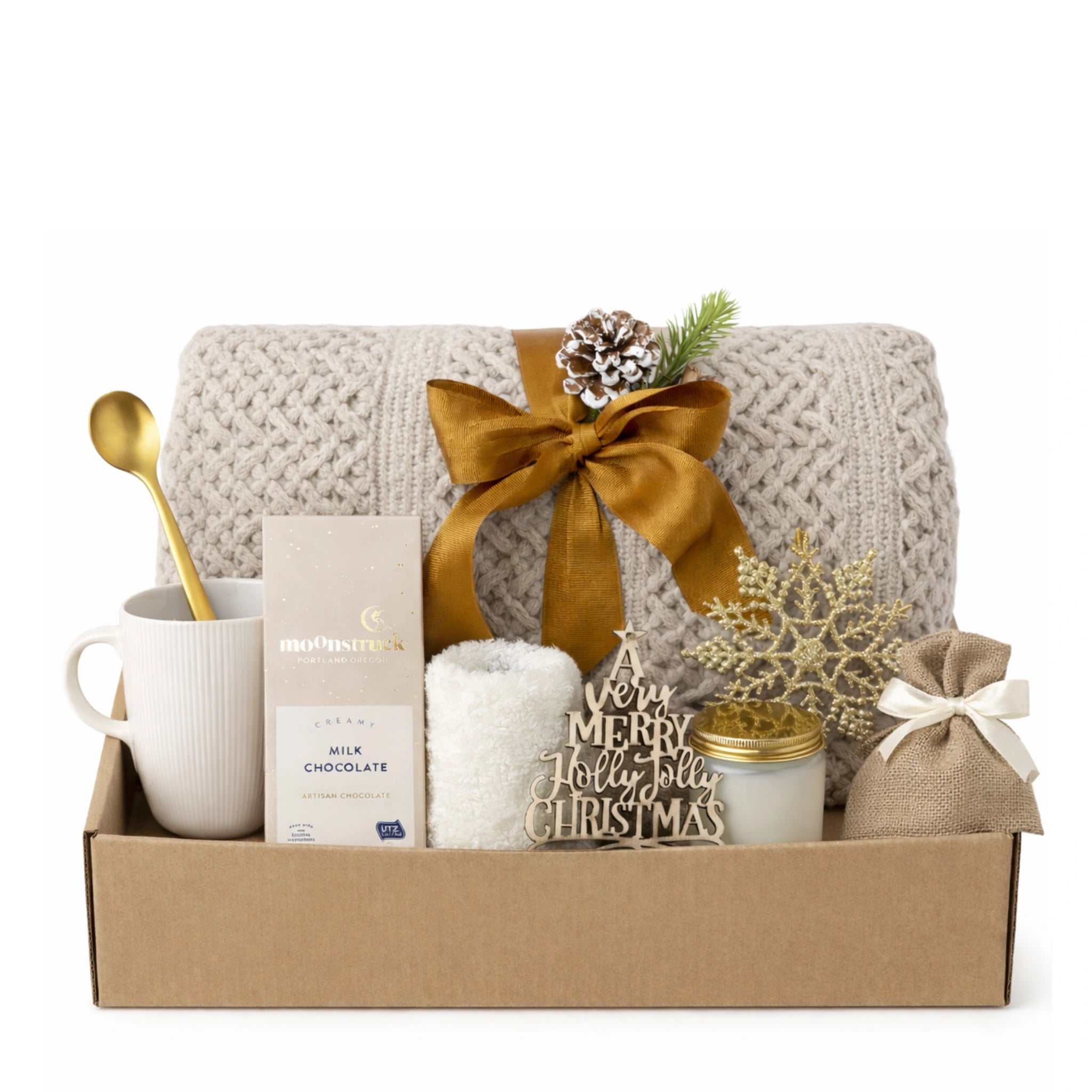 All I Want is You Gift Box holiday set arranged inside open kraft box with beige knitted throw blanket, white ceramic mug, Moonstruck milk chocolate, white fluffy socks, glass candle with gold lid, burlap bag, golden spoon, and festive Christmas ornaments.