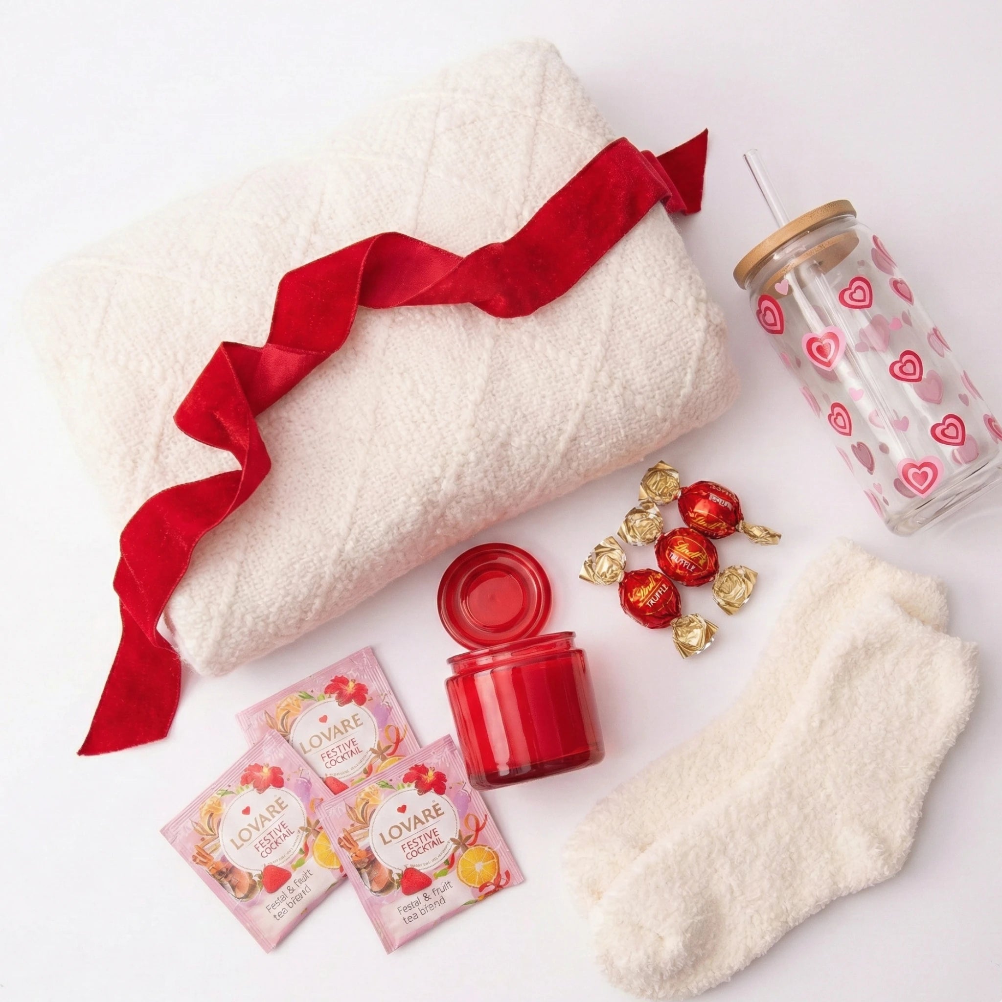 Top down flat lay view of All My Love box items including white textured blanket, fuzzy socks and festive tea