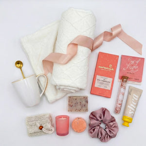 Top down flat lay view of Beautifully Unique box items including pink candle, bath salt and chocolate