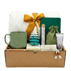Calm Holiday self-care gift basket with bath salt, Christmas tree candle, mug, and blanket by Arinna Gifts in Dallas