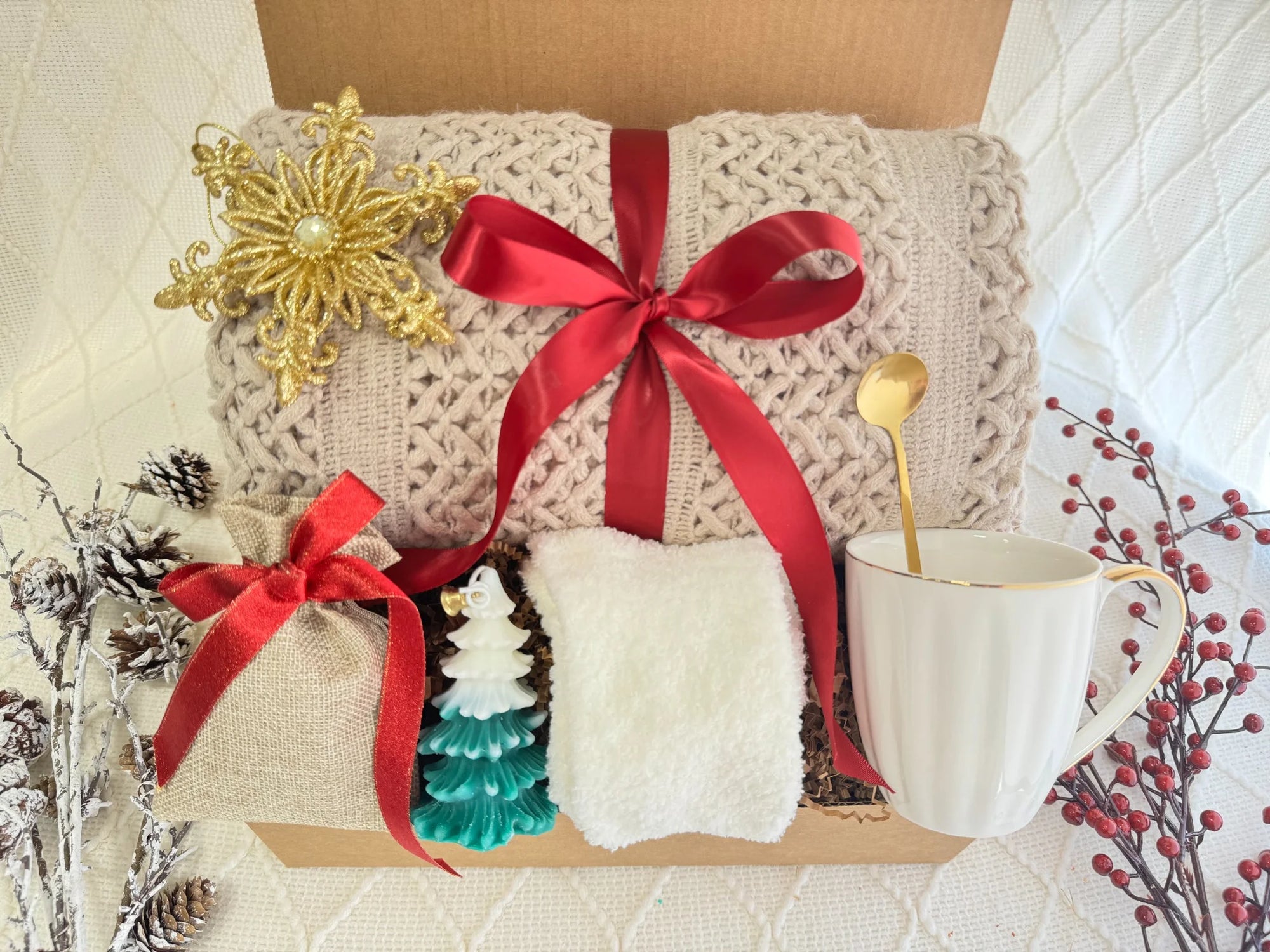 ift box with blanket, mug, fluffy socks, golden spoon, candle, and Christmas decorations