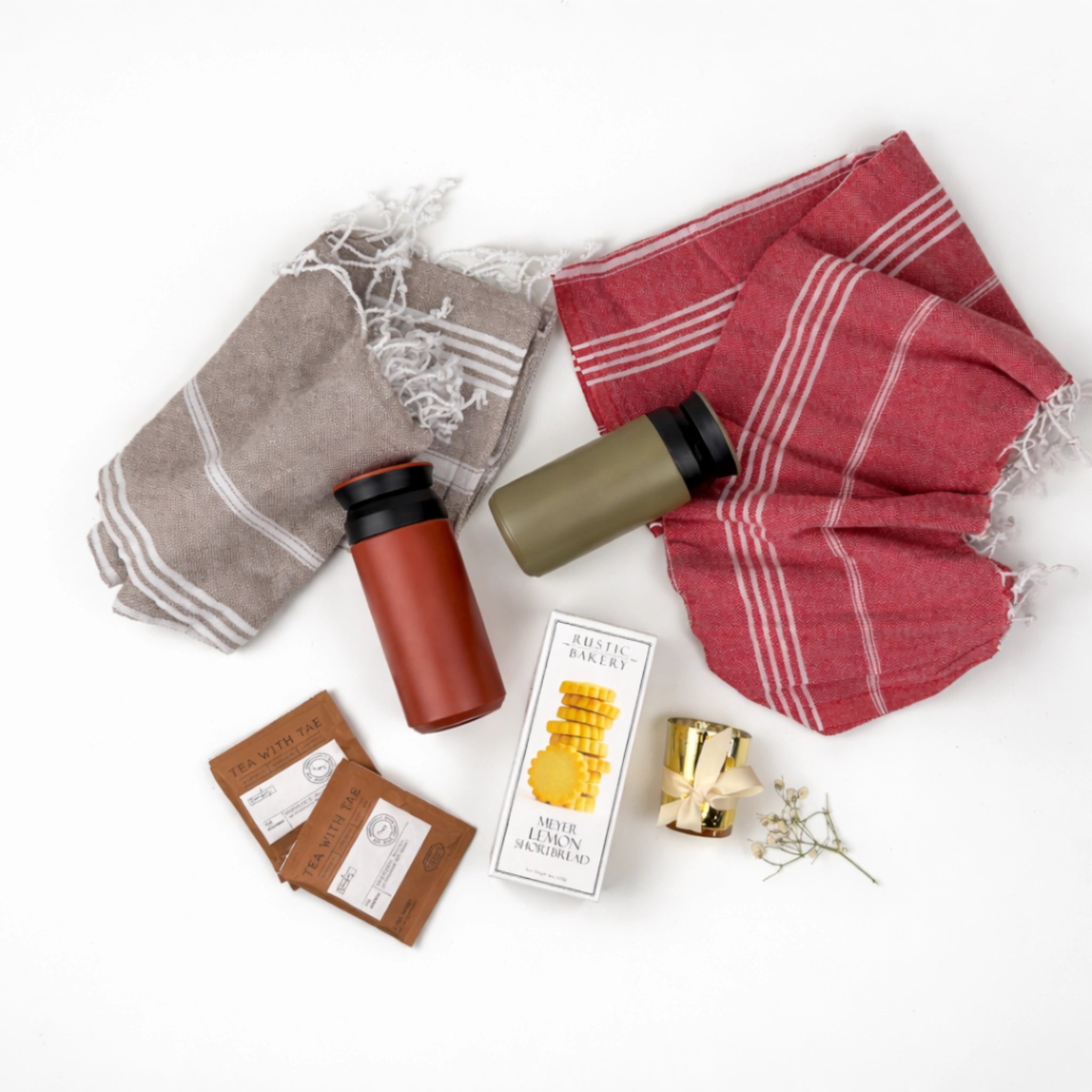 Flat lay coastal couple gift box featuring Turkish cotton beach towels, insulated tumblers, herbal tea sachets, shortbread cookies and candle holder