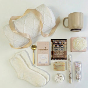 Top down flat lay view of Contentment box items including rose candle, bath salt and fluffy socks