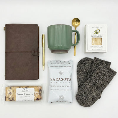 Top down flat lay view of Men's coffee gift set items including olive oil crackers and caramel coffee