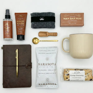 Top down flat lay view of Gentlemans Gift Box items including beige mug and grooming essentials