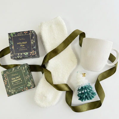 Top down flat lay view of Jingle Bells box items including Christmas tree candle and gourmet cookies
