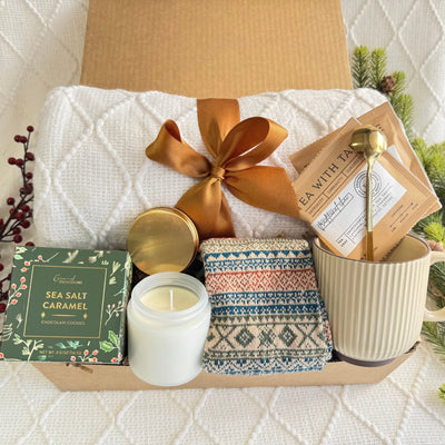 Merry Christmas Gift Box featuring a throw blanket, Nordic socks, gourmet cookie, coffee mug, golden coffee spoon, herbal tea, scent candle, and snowflake Christmas ornament.