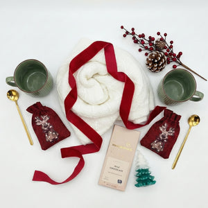 Top down flat lay view of Merry Cozy Duo box items including two mugs and hot chocolate bags