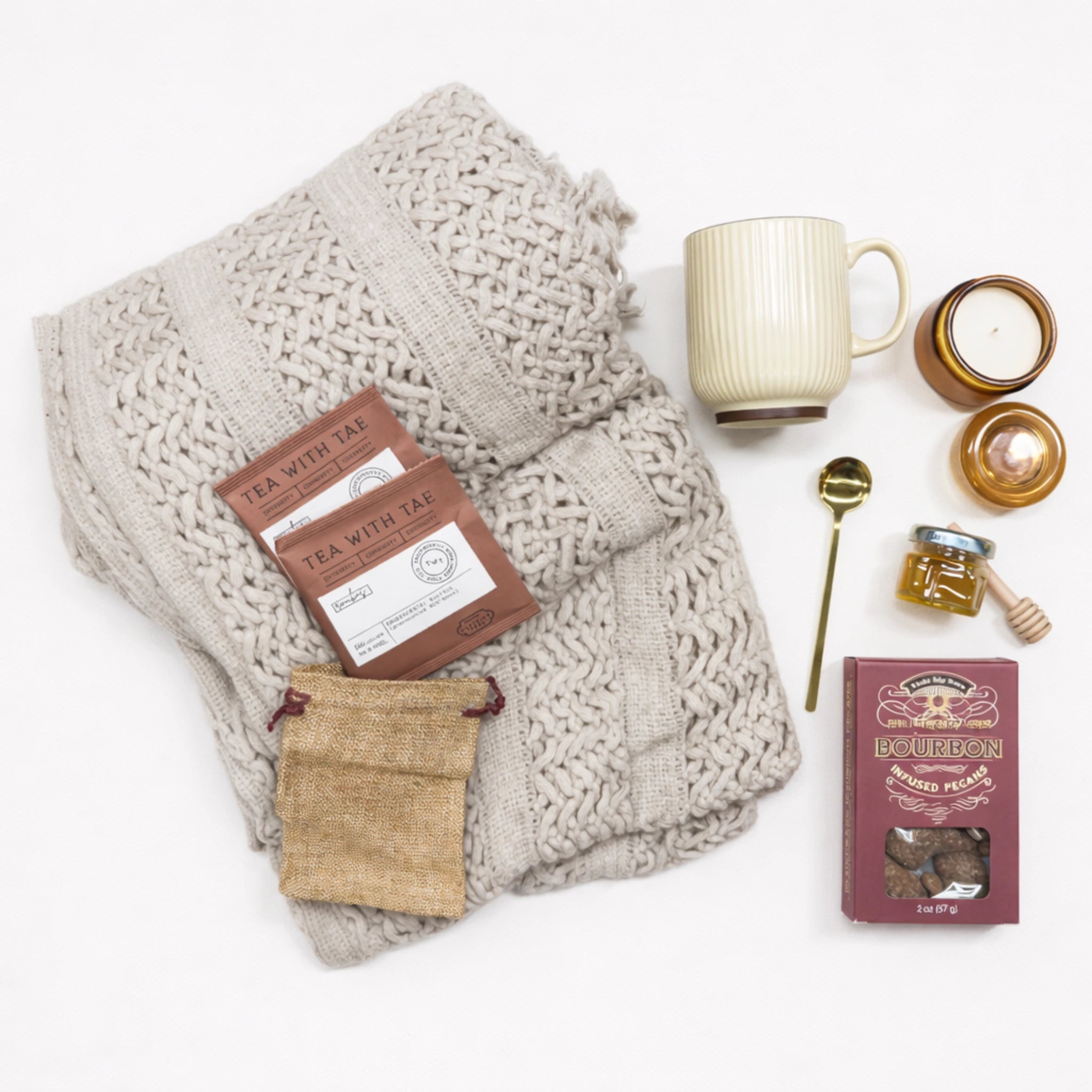 Flat lay of Quiet Comfort Gift Box care package for women featuring cozy blanket, herbal tea, honey, candle and ceramic mug