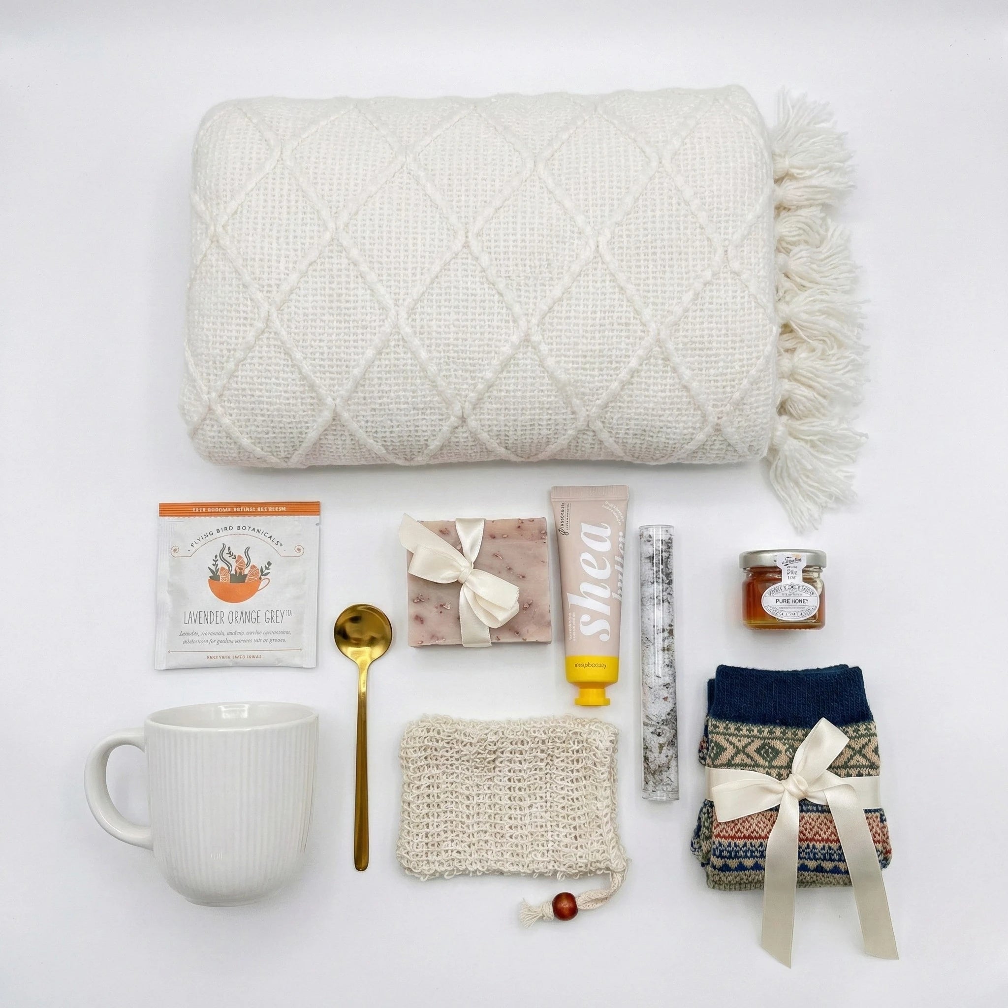 Top down flat lay view of spa gift set items including patterned socks, honey jar, and botanical soap