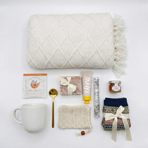 Top down flat lay view of spa gift set items including patterned socks, honey jar, and botanical soap