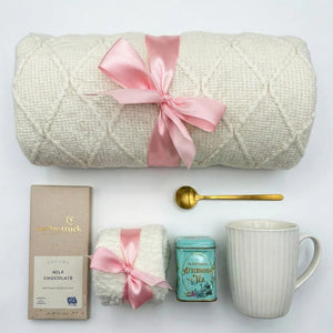 Top down flat lay view of Sending Love box items including afternoon tea tin and fluffy socks