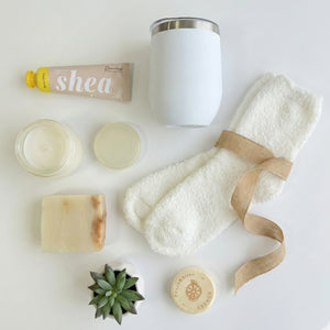 Top down flat lay view of Take It Easy box items including shea cream, candle and fluffy socks
