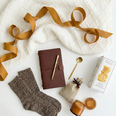 Top down flat lay view of Warm Hugs box items including vintage journal and hot chocolate burlap bag